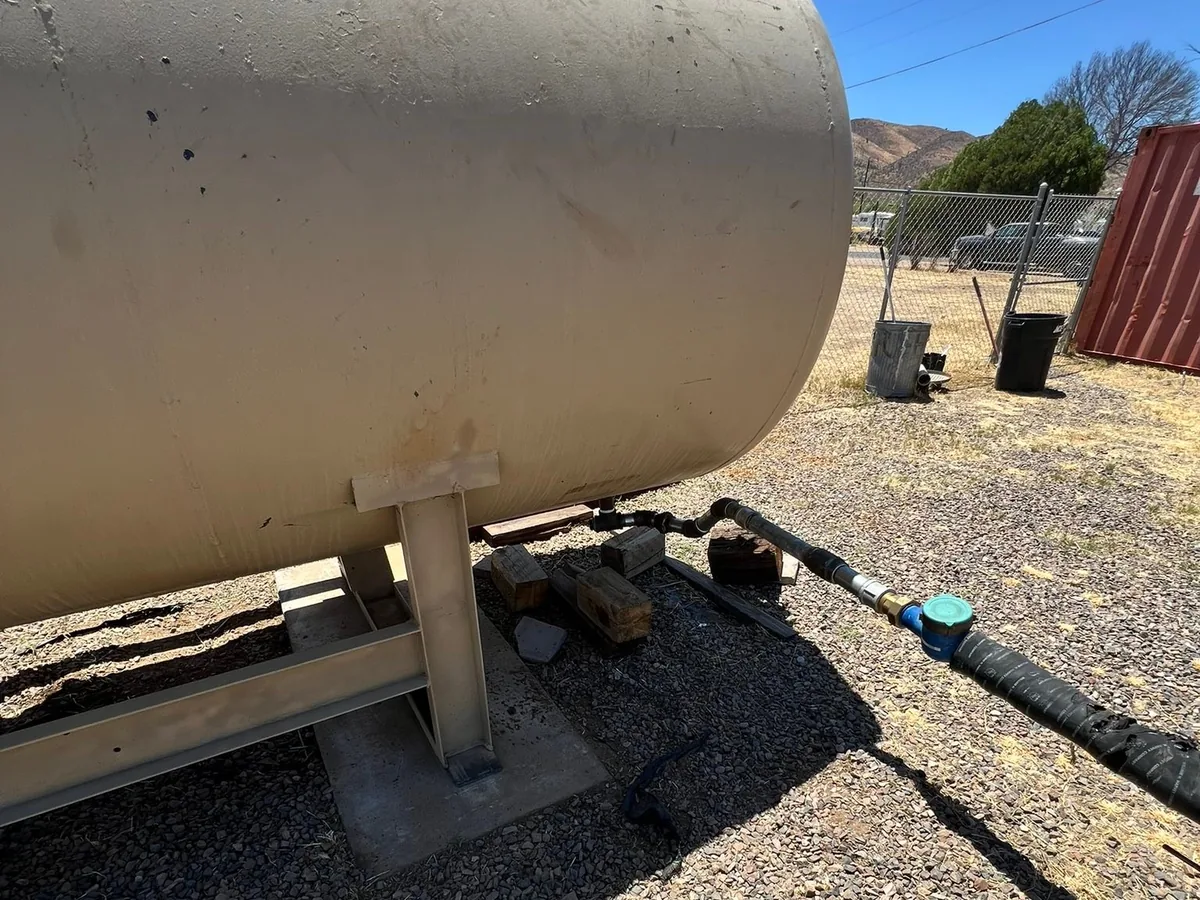 Rebuilt steel water storage tank set back on its stand with new plumbing