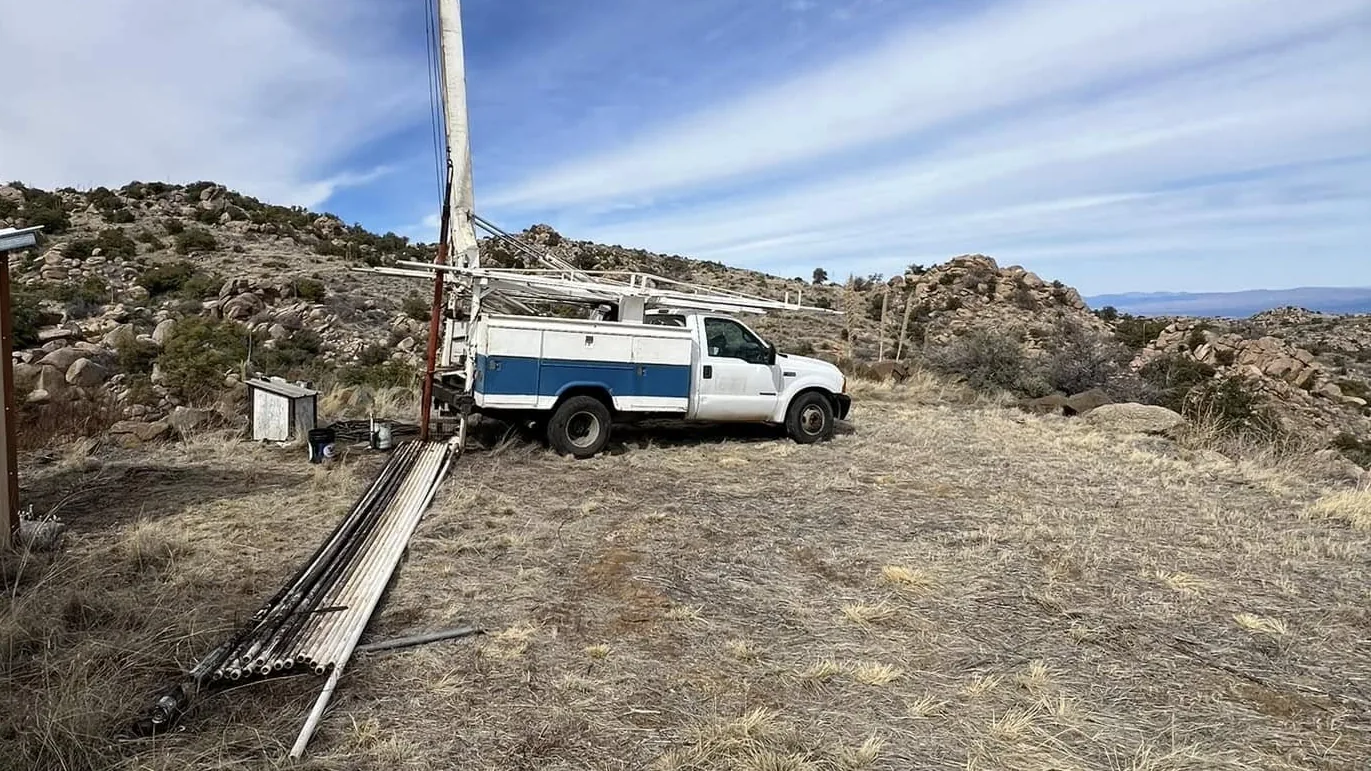 Pump hoist truck with the mast up over a well on an Arizona desert hillside