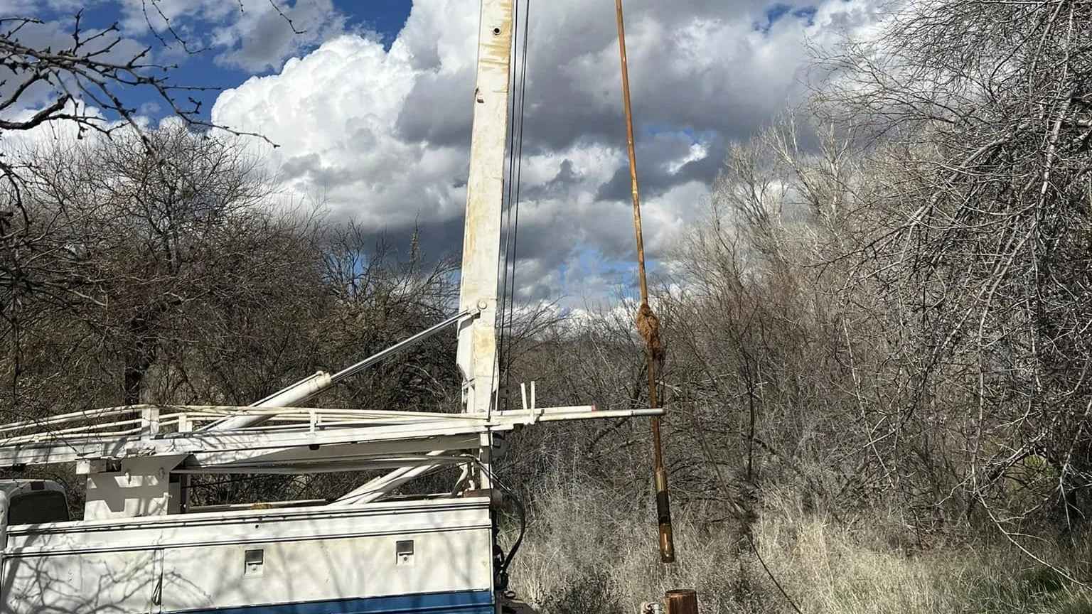 Pump hoist truck with the mast raised over a well under Arizona storm clouds