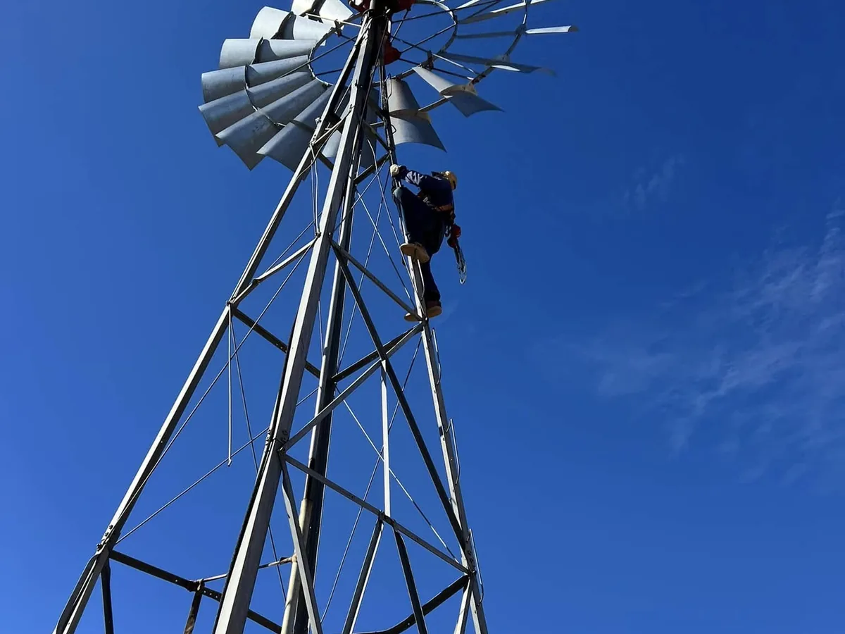 Harnessed technician working high on a windmill tower